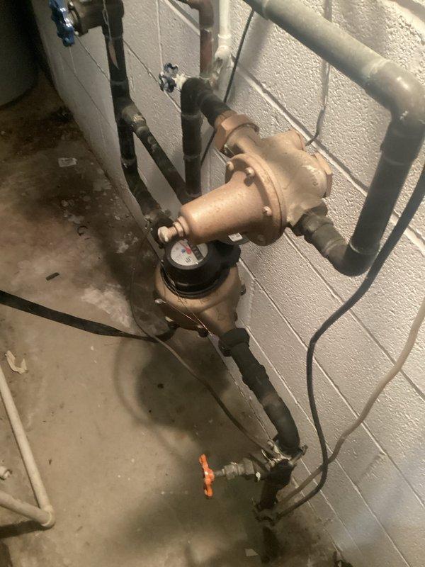 Conducted assessment for customer's light fixture replacement needs and evaluated non-functioning dryer breaker issue. Inspection revealed outdated electrical panel with disorganized wiring configuration and potentially problematic circuit breakers. Documented current plumbing installation with pressure regulator valve and multiple pipe connections for reference during electrical work planning.