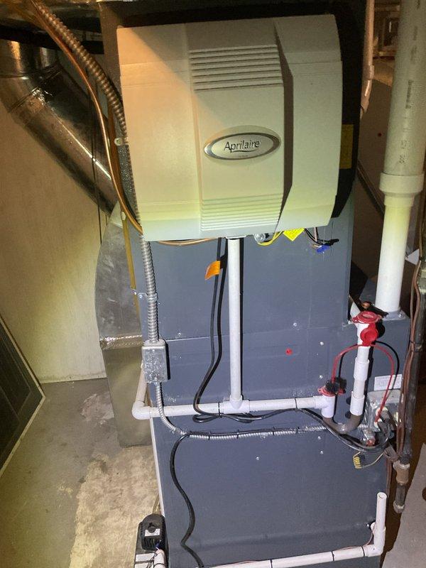 Responded to customer-reported water leak from furnace. Upon inspection, identified a leak from the Aprilaire humidifier mounted on the furnace unit. Tightened loose connection on the humidifier's water supply line and verified proper drainage through the PVC pipe system. Tested system operation to confirm leak was resolved.