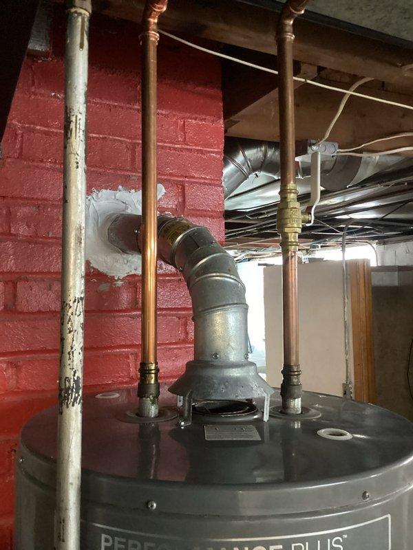 Responded to customer complaint of water leakage around the base of their Rheem Performance Plus water heater. Conducted full inspection of the unit, noting significant corrosion on one of the connecting pipes. Replaced the deteriorated pipe, sealed the tank base properly, and verified proper venting through the wall penetration. System now operating correctly with no leaks detected.