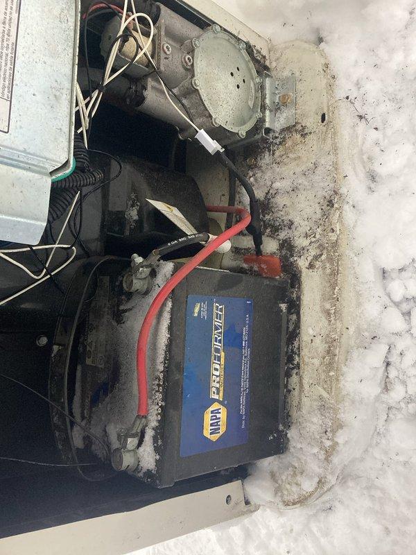 Performed warranty service on Generac unit. Inspected interior compartment including insulated walls, rubber hoses, and electrical components with warning labels. Examined battery installation and connections, noting NAPA ProForce battery with cable terminal attachment. Observed accumulation of dust and possible corrosion on housing components requiring cleaning.