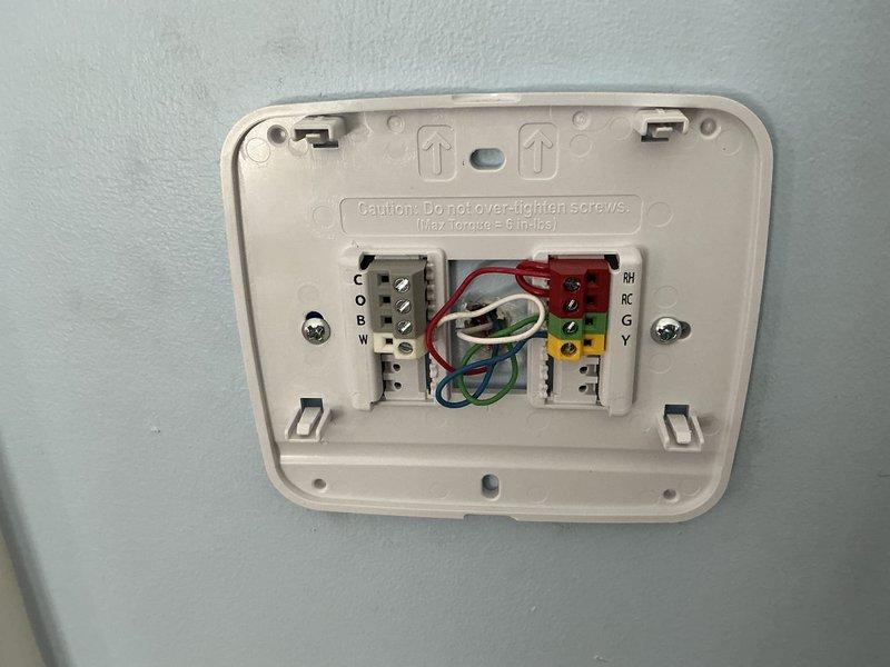 Performed diagnostic assessment on west side HVAC system which was exhibiting leakage issues and requiring high-cost repairs. Inspected furnace/air handler unit (labeled "#2") with connected refrigerant lines and valve assembly. Examined thermostat wiring configuration, noting proper terminal connections for C, O, B, W and RH, RC, G, Y circuits, which appeared intact with no visible damage.