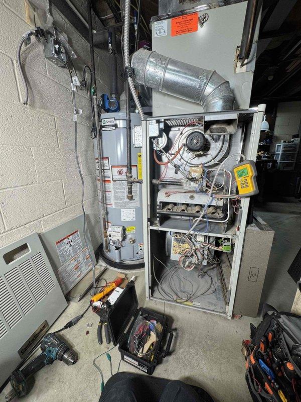 Diagnosed no heat issue on 10+ year old furnace system. Removed front panel to inspect internal components and used UEi EM201B digital meter to test electrical readings, obtaining +0.096 measurement. Determined igniter malfunction was preventing proper heating despite functional blower operation. Replaced faulty igniter and verified complete system operation before concluding service.