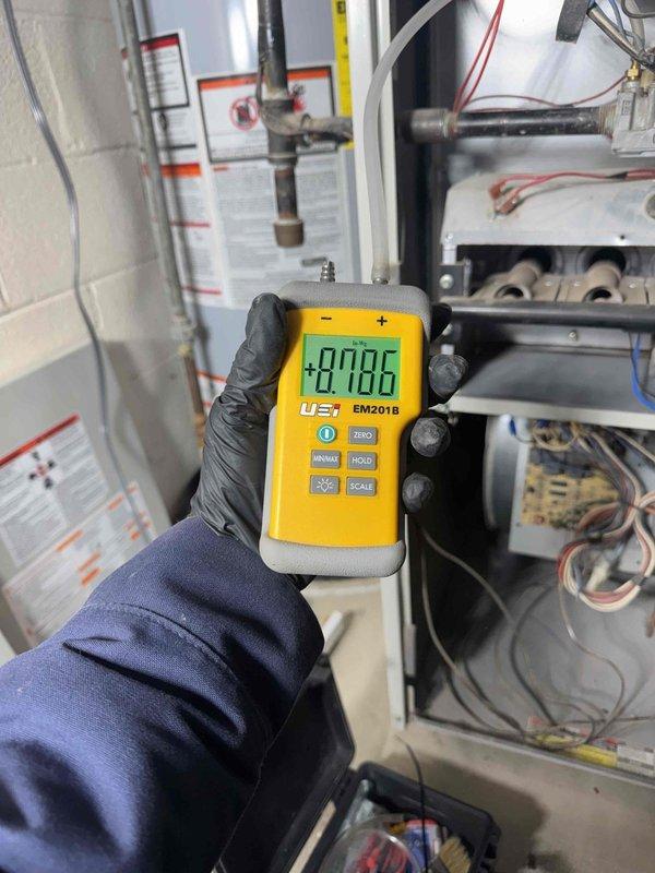 Diagnosed no heat issue on 10+ year old furnace system. Removed front panel to inspect internal components and used UEi EM201B digital meter to test electrical readings, obtaining +0.096 measurement. Determined igniter malfunction was preventing proper heating despite functional blower operation. Replaced faulty igniter and verified complete system operation before concluding service.