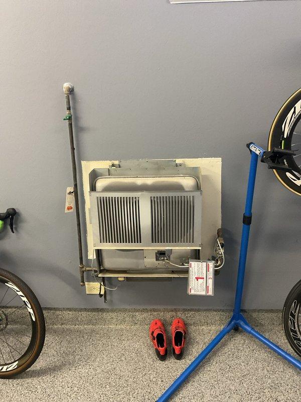 Diagnosed non-operational garage heater unit. Inspected wall-mounted convection heater showing signs of age and wear. System appears to be installed in a garage space used for bicycle storage. Recommended replacement options due to unit's condition and inefficient operation.