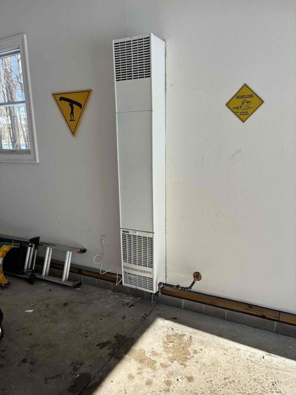 Successfully installed a Williams through-the-wall garage heater with proper electrical connections and ventilation. Unit was mounted securely on concrete wall with copper piping installed at the base for proper functionality. Appropriate safety signage was placed on both sides of the unit per regulations.