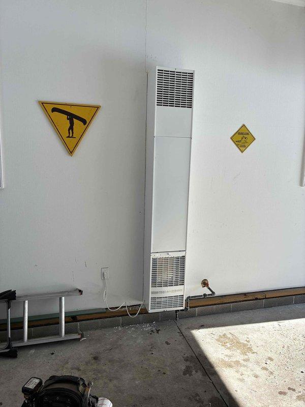 Successfully installed a Williams through-the-wall garage heater with proper electrical connections and ventilation. Unit was mounted securely on concrete wall with copper piping installed at the base for proper functionality. Appropriate safety signage was placed on both sides of the unit per regulations.