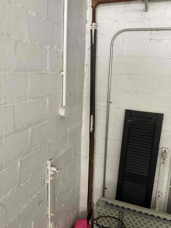 Responded to emergency no-heat call for a radiant heating system with a boiler less than 5 years old. Upon inspection, discovered a major leak in an unidentified line (either supply or return) located in the garage. Documented the condition with photos of the plumbing connections and valve assembly for further assessment.