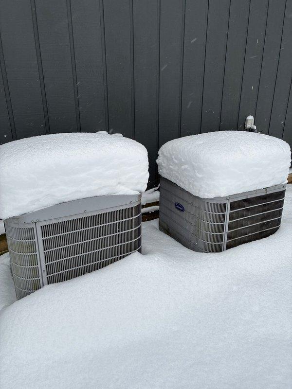 Performed assessment of non-functioning heating system. Inspected Carrier furnace and air handler unit in basement showing signs of water damage underneath. Exterior inspection revealed two Carrier condensers heavily covered in snow. Recommended full system replacement due to age and condition of equipment, with multiple replacement options presented to homeowner for the main heating system.