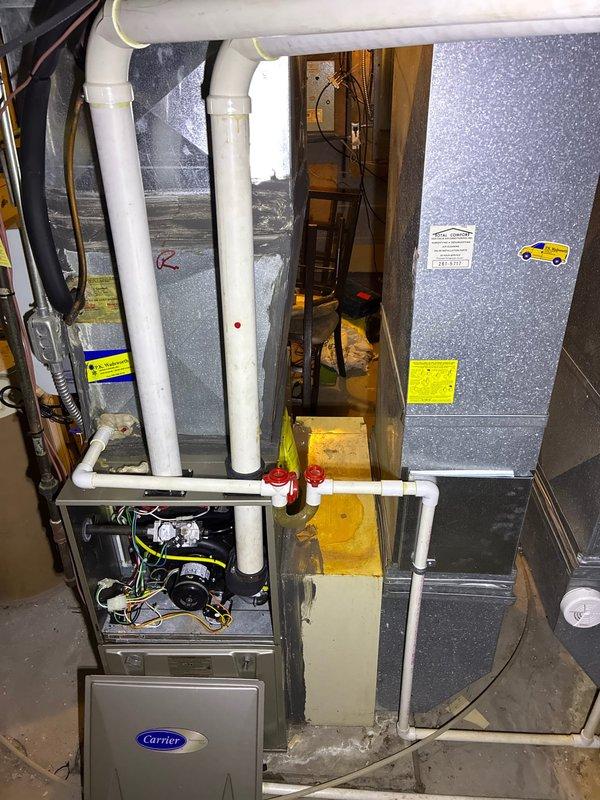 Performed assessment of non-functioning heating system. Inspected Carrier furnace and air handler unit in basement showing signs of water damage underneath. Exterior inspection revealed two Carrier condensers heavily covered in snow. Recommended full system replacement due to age and condition of equipment, with multiple replacement options presented to homeowner for the main heating system.