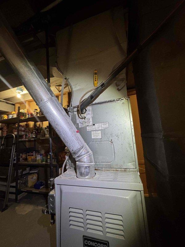 Performed a system check for new homeowners on Concord furnace unit located in basement. Inspected ductwork connections and overall heating system installation. Temperature readings taken with digital measurement tool confirmed normal operating parameters at 1200°F.