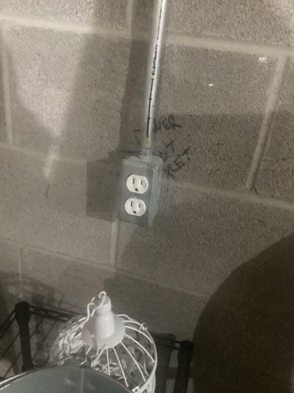 Conducted electrical inspection of residential panel system. Examined outlet installation on cinder block wall with conduit routing and verified proper grounding. Inspected adjacent HVAC system including Rheem unit and associated electrical connections.