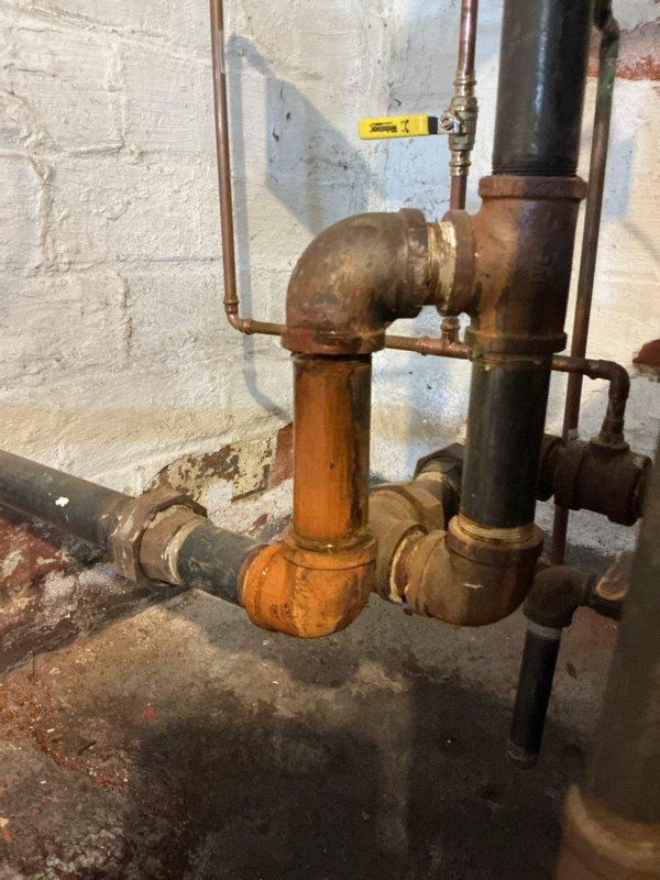 Responded to customer report of boiler leak. Upon inspection, identified significant oxidation and corrosion on copper supply lines and brass fittings, particularly at 90-degree elbow joints. System shows signs of age with extensive rusty orange patina development on multiple pipe sections that requires attention to prevent future leakage issues.
