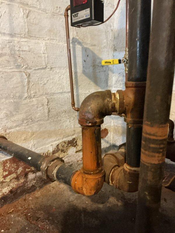 Responded to customer report of boiler leak. Upon inspection, identified significant oxidation and corrosion on copper supply lines and brass fittings, particularly at 90-degree elbow joints. System shows signs of age with extensive rusty orange patina development on multiple pipe sections that requires attention to prevent future leakage issues.