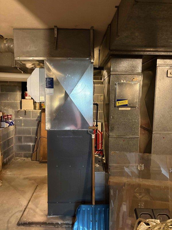 Successfully installed new furnace system in basement utility area. Unit features proper electrical connections with junction box and conduit, along with PVC drainage/ventilation piping. System includes appropriate ductwork connections with rectangular metal ducting extending to existing distribution network.