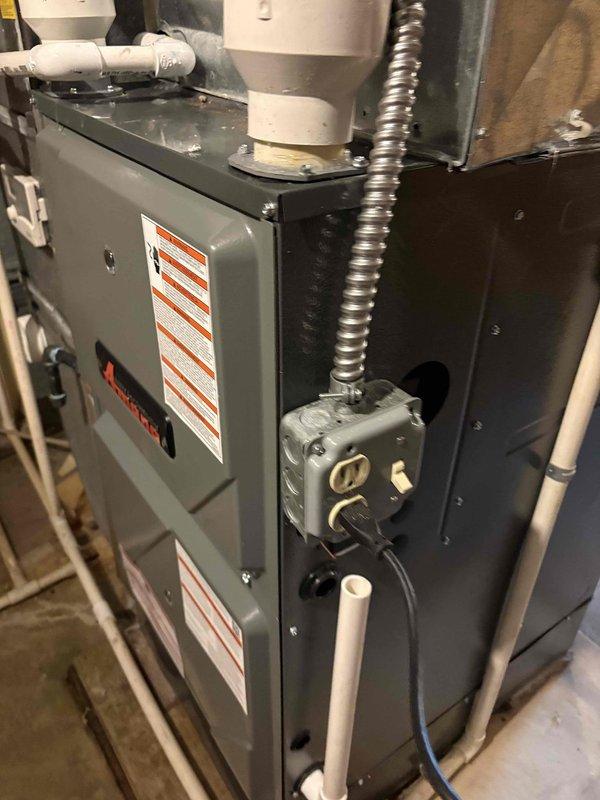 Successfully installed new furnace system in basement utility area. Unit features proper electrical connections with junction box and conduit, along with PVC drainage/ventilation piping. System includes appropriate ductwork connections with rectangular metal ducting extending to existing distribution network.