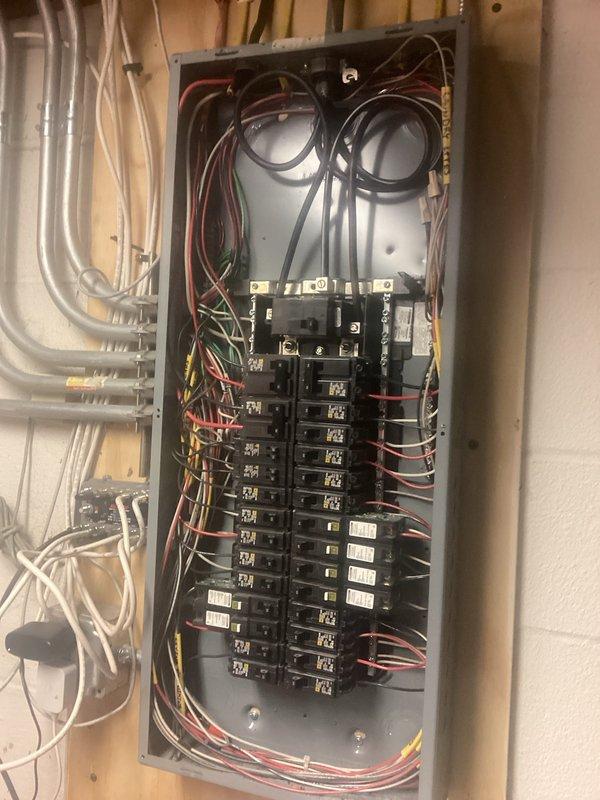 Performed comprehensive electrical panel inspection, examining interior components of breaker box with cover removed. Verified proper wire connections, breaker functionality, and overall panel condition. All circuit breakers and wiring (including red, black, white, and green conductors) appeared properly installed with no visible damage or safety concerns noted.