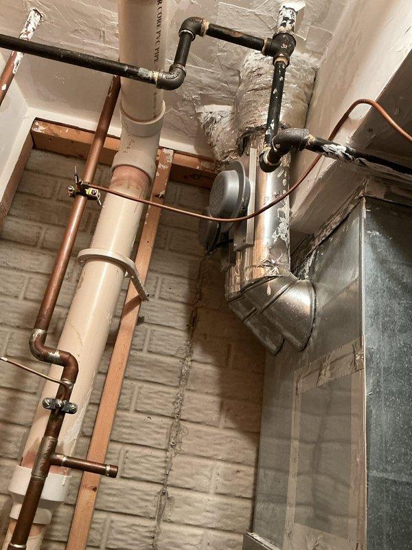 Completed scheduled SPP maintenance tune-up on wall-mounted HVAC system. Inspected air handler unit mounted on concrete block wall, checking all connections including the blue valve component. Examined adjacent plumbing infrastructure including copper pipes and PVC installation. All components functioning properly with no issues detected.