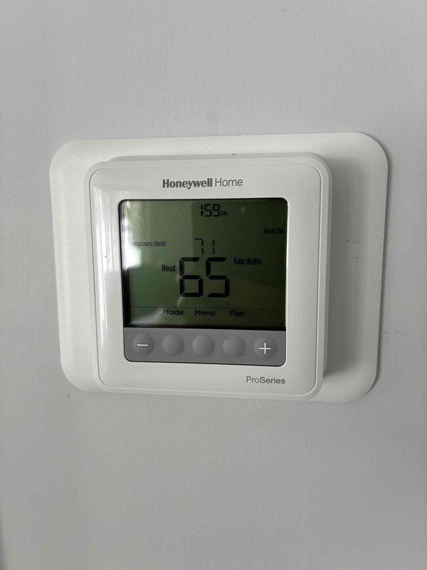 Completed furnace installation with integrated Honeywell ProSeries thermostat and AprilAire humidifier. Verified system functionality with thermostat operating in heat mode at 65°F and humidifier control panel displaying 28% humidity with proper indicator lights functioning. All electrical connections properly secured with appropriate wire routing.