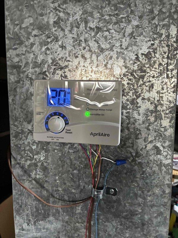Completed furnace installation with integrated Honeywell ProSeries thermostat and AprilAire humidifier. Verified system functionality with thermostat operating in heat mode at 65°F and humidifier control panel displaying 28% humidity with proper indicator lights functioning. All electrical connections properly secured with appropriate wire routing.