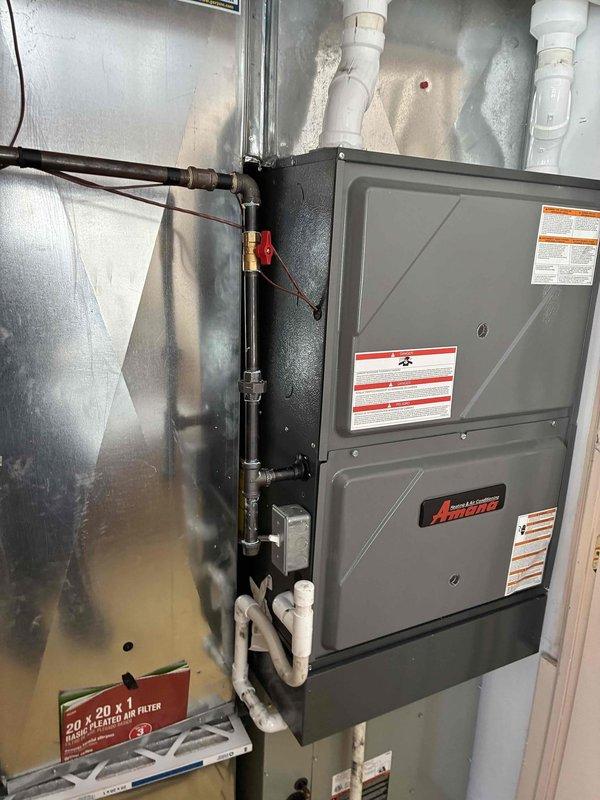 Completed installation of new Amana furnace in utility closet with proper venting, including installation of dual white PVC exhaust pipes, copper gas line connection with shutoff valve, and condensate drainage system. Unit was properly mounted with reflective heat shielding, all manufacturer labels intact, and a new 20x20x1 air filter was provided for the system.