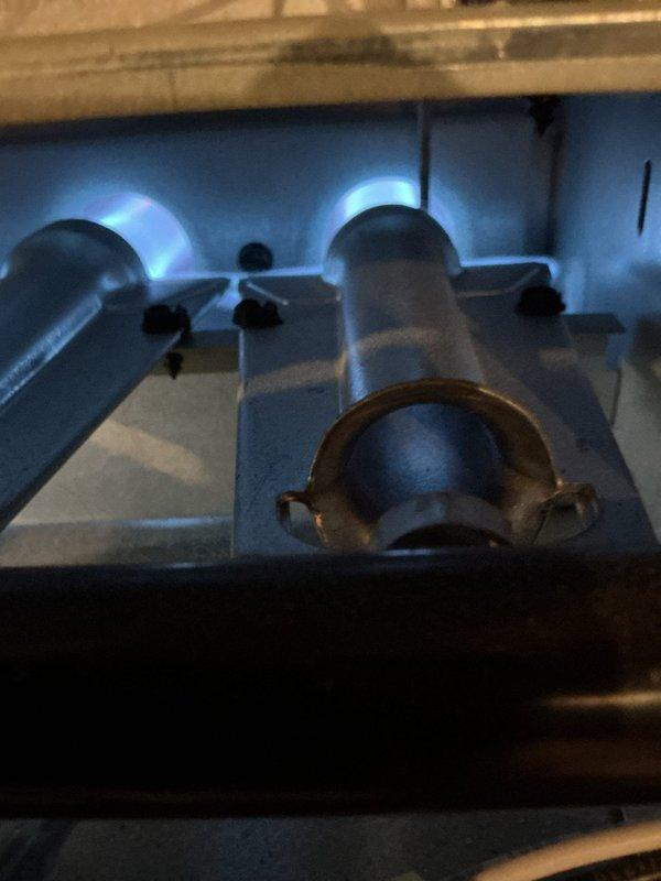 Responded to no heat call for customer's furnace. Upon inspection, performed electrical diagnostics with clamp meter showing low amperage (04) reading. Visual inspection of burner assembly revealed only two operational burner tubes with weak blue flames, indicating gas flow issues. Cleaned flame sensor, checked gas pressure, and adjusted gas valve to restore proper combustion across all burners. System now operating within normal parameters with adequate heat output.