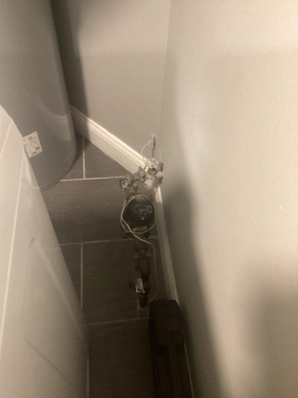 Conducted electrical inspection of utility area, examining wall-mounted electrical panel and verifying proper connections to laundry appliances. Inspected plumbing-adjacent wiring in bathroom corner to ensure code compliance and safe operation.