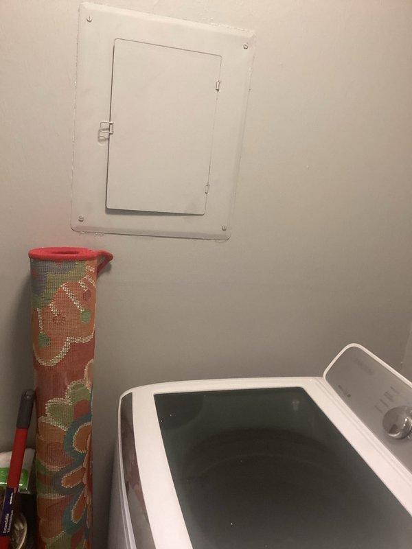 Conducted electrical inspection of utility area, examining wall-mounted electrical panel and verifying proper connections to laundry appliances. Inspected plumbing-adjacent wiring in bathroom corner to ensure code compliance and safe operation.