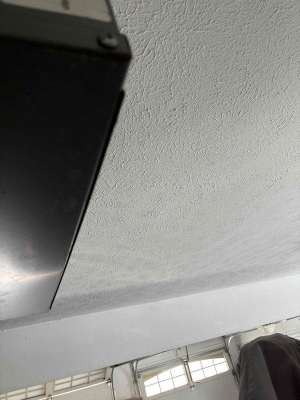 Conducted inspection and provided quote for garage heater replacement. Current installation shows aging unit with flexible metal ductwork connected to ceiling-mounted register. Noted textured ceiling condition and existing ventilation configuration for proper replacement specifications.