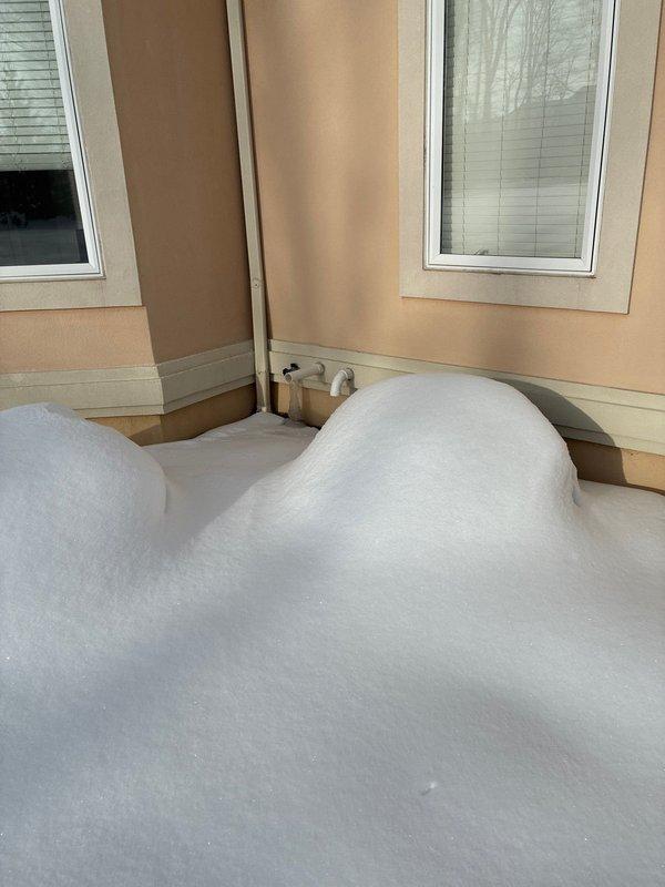 Conducted assessment for larger furnace replacement options. Current furnace shows significant aging with visible rust damage. Documented existing water heater installation and exterior conditions, noting substantial snow accumulation around the property that may impact installation logistics.