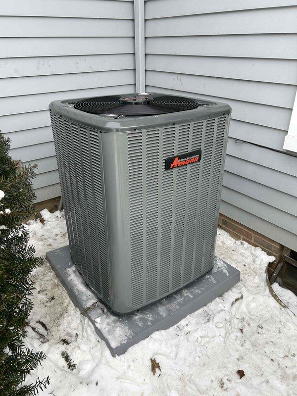 Successfully installed complete HVAC system including 96% efficient Amana furnace, matching Amana air conditioning unit, Aprilaire humidifier, and 50-gallon hot water tank. System features proper PVC venting, secure outdoor condenser placement on concrete pad, and complete ductwork connections for optimal performance and efficiency.