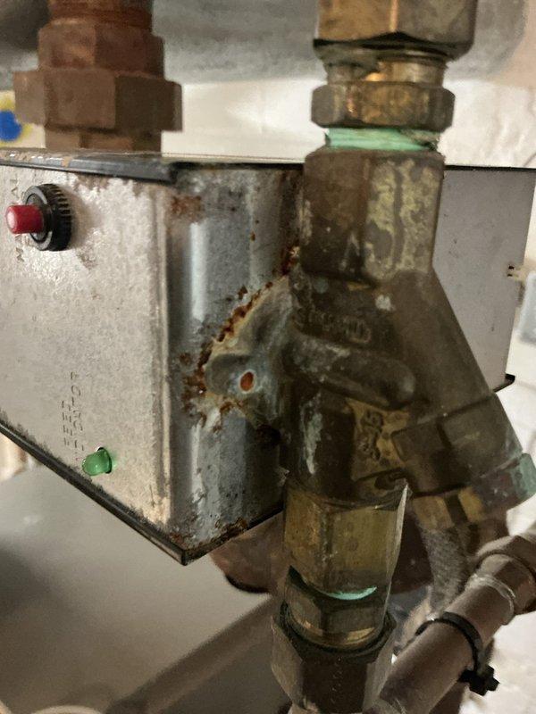 Performed comprehensive inspection of aging boiler system for new homeowner. Noted significant corrosion on control box and brass fittings, particularly at the Y-shaped valve assembly. Examined water level indicator tube and verified proper functioning of the red valve handle that controls water flow. System operational despite visible wear and oxidation on components.