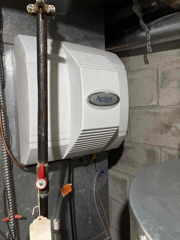 Responded to service call regarding continuous water drainage from Aprilaire whole-house humidifier. Inspected system and found severely clogged air filter causing improper system operation. Serviced humidifier components and replaced filter to restore proper functionality and eliminate water waste issue.