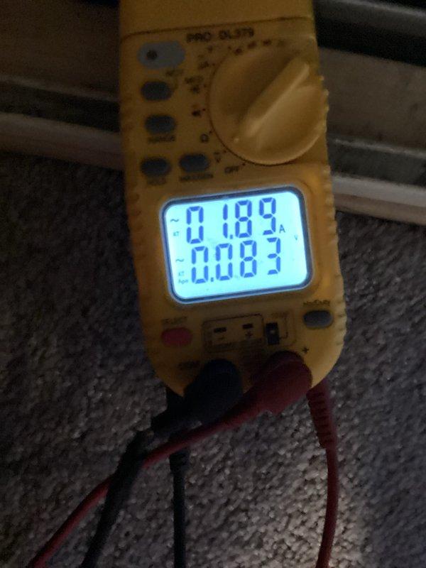 Performed monthly heating system maintenance on a furnace unit. Conducted electrical testing using multimeter to verify proper voltage and amperage readings (0.189A/0.083V). Inspected internal components with front panel removed, checking motor function and ventilation/drainage connections.