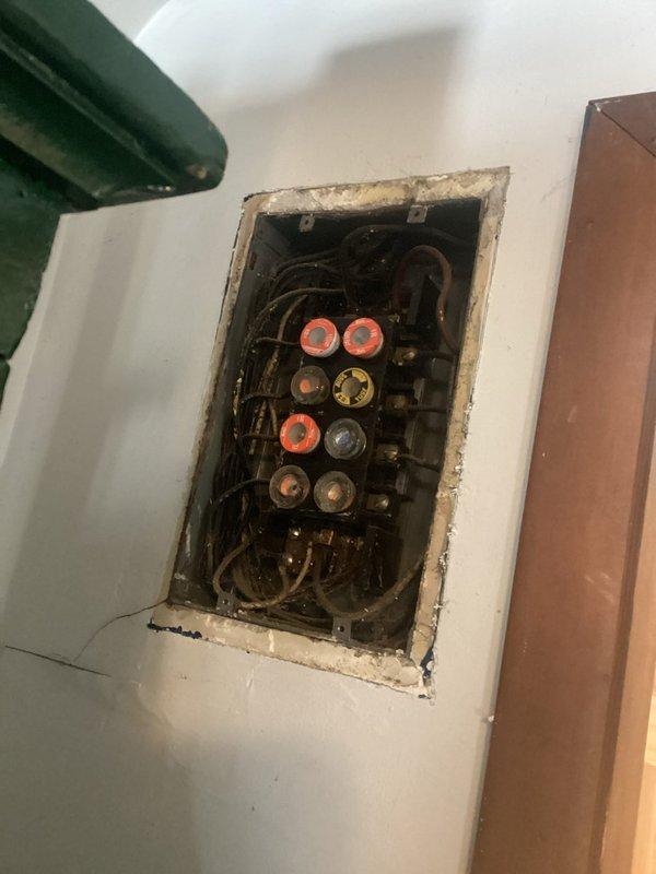 Conducted comprehensive inspection of outdated fuse panel system with multiple screw-in fuses showing signs of wear. Documented significant concerns including disorganized wiring, deteriorated insulation, and panel installation that fails to meet current electrical code requirements. Provided detailed estimate for complete home rewiring to address safety hazards and bring electrical system up to modern standards.