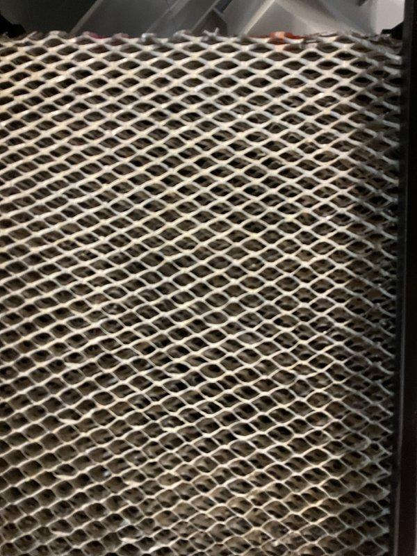Performed routine heating maintenance on P.K. Wadsworth furnace system in basement utility room. Inspected and cleaned the filtration system, noting slight dust accumulation on the metal mesh filter. All ventilation components, including PVC exhaust pipes, were verified to be properly connected and functioning correctly.