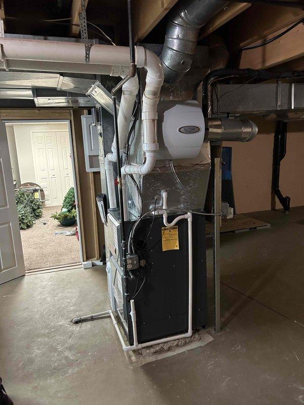 Successfully installed a complete 96% efficient Amana furnace system with integrated air conditioning and air scrubber in a basement utility area. System includes properly connected PVC ventilation pipes, sealed metal ductwork, and all required components mounted securely with appropriate clearances. Final inspection confirmed proper operation of all system components.