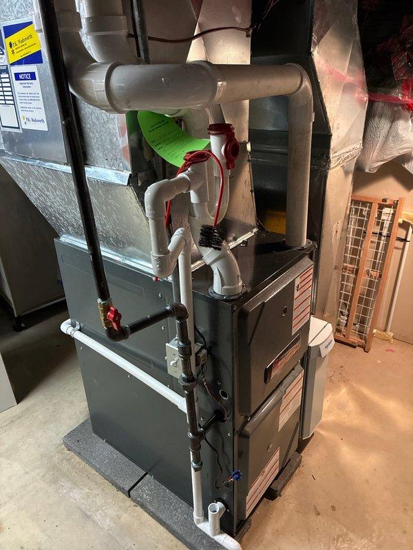 Completed installation of a 96% efficient furnace with humidifier in customer's utility room. System includes proper PVC ventilation with required drainage components and is fully operational after addressing no-heat situation. Unit was mounted on protective pad with all connections secured and tested.