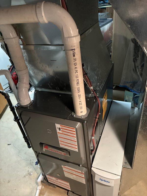 Completed installation of a 96% efficient furnace with humidifier in customer's utility room. System includes proper PVC ventilation with required drainage components and is fully operational after addressing no-heat situation. Unit was mounted on protective pad with all connections secured and tested.