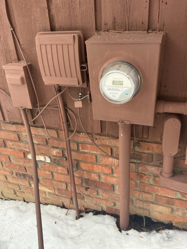 Conducted comprehensive electrical inspection of exterior meter installation and interior electrical components. Inspected main meter showing 0.185 reading, junction boxes, and associated wiring on building exterior. Also examined electrical connections to water treatment system including Kinetico tank, pressure vessel, and copper/PVC plumbing infrastructure with particular attention to electrical safety near water systems.