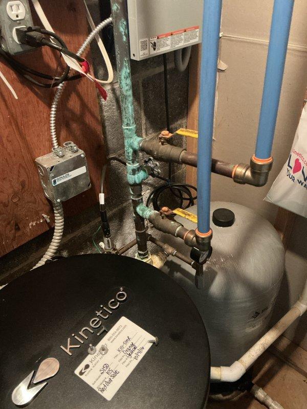 Conducted comprehensive electrical inspection of exterior meter installation and interior electrical components. Inspected main meter showing 0.185 reading, junction boxes, and associated wiring on building exterior. Also examined electrical connections to water treatment system including Kinetico tank, pressure vessel, and copper/PVC plumbing infrastructure with particular attention to electrical safety near water systems.