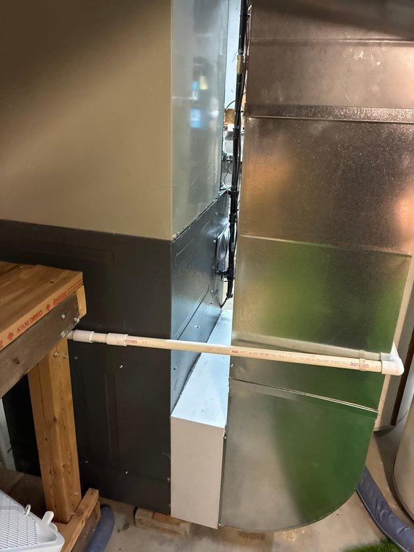 Successfully completed installation of a new furnace with complete metal ductwork system and proper PVC drainage piping. System includes a rectangular metal cabinet housing with round metal duct extending to the main air distribution network, positioned adjacent to the existing water heater in the utility area.