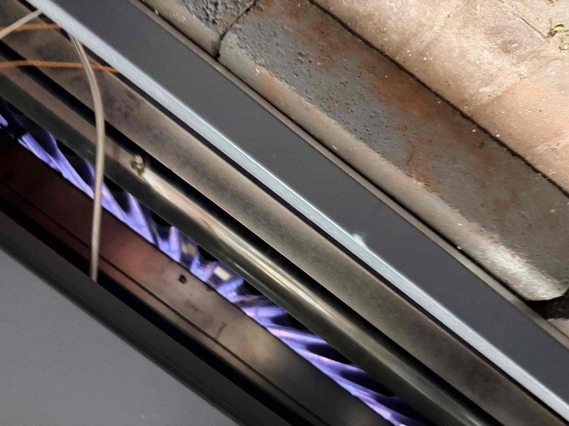 Responded to service call for cold conditions in church lower level. Inspected main boiler system in basement, confirming proper flame pattern and complete combustion with characteristic blue flames. Checked pressure gauge readings and examined two additional wall-mounted heating units to verify functionality and proper operation of all heating systems.