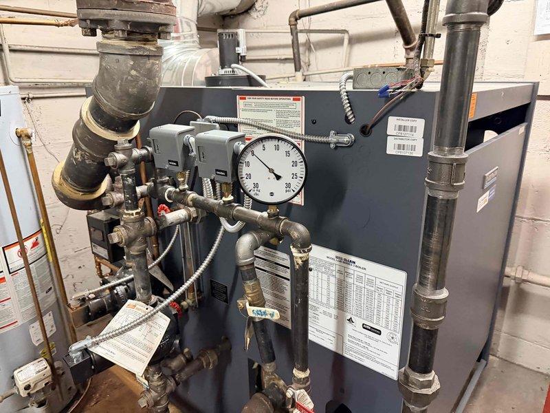 Responded to service call for cold conditions in church lower level. Inspected main boiler system in basement, confirming proper flame pattern and complete combustion with characteristic blue flames. Checked pressure gauge readings and examined two additional wall-mounted heating units to verify functionality and proper operation of all heating systems.