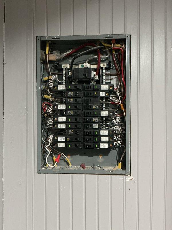 Conducted a comprehensive electrical panel inspection, examining the 120/240V distribution panel which contains properly labeled circuit breakers with indicator lights. Observed organized wiring configuration with appropriate color coding (black/red hot wires, white neutrals) and noted the adjacent Navien water heater system (set to 120°F) with PEX and copper piping connections.