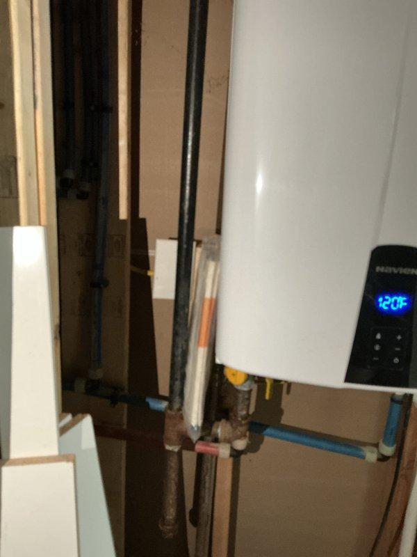 Conducted a comprehensive electrical panel inspection, examining the 120/240V distribution panel which contains properly labeled circuit breakers with indicator lights. Observed organized wiring configuration with appropriate color coding (black/red hot wires, white neutrals) and noted the adjacent Navien water heater system (set to 120°F) with PEX and copper piping connections.