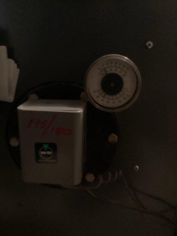 Completed routine maintenance on aging heating system (10+ years old). Inspected control box with green indicator light functioning properly and verified pressure readings on analog gauge were within normal parameters. System includes boiler unit with associated copper piping, circulator pump, and flue components - all operational with no immediate concerns identified.