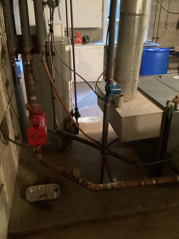 Completed routine maintenance on aging heating system (10+ years old). Inspected control box with green indicator light functioning properly and verified pressure readings on analog gauge were within normal parameters. System includes boiler unit with associated copper piping, circulator pump, and flue components - all operational with no immediate concerns identified.