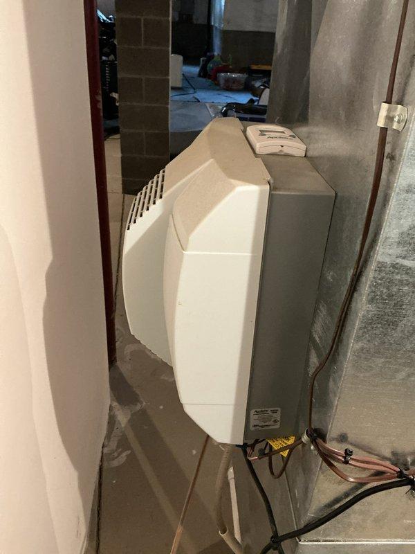 Performed biannual heating maintenance on system that is over 10 years old. Inspected interior components including wiring connections and seals, noting some dust accumulation. Examined the main unit housing and connected copper lines, with particular attention to the ventilation system components in the basement installation area.