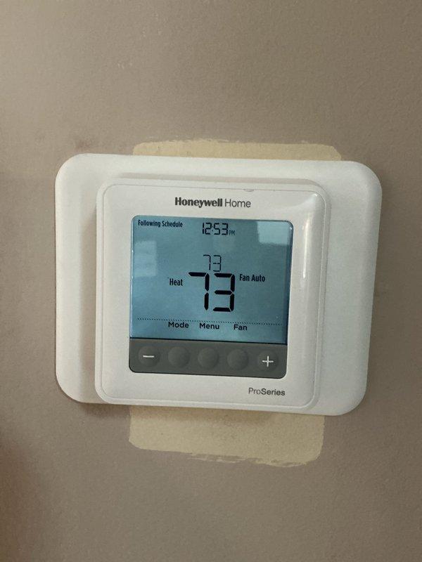 Responded to customer complaint regarding uneven heating and cold air during furnace startup. Inspected Honeywell ProSeries thermostat which was operating normally at 73°F in heat mode. Examined plumbing connections to the HVAC system, including copper piping, brass valve assemblies, and pressure regulator, finding all components properly installed and functioning correctly.