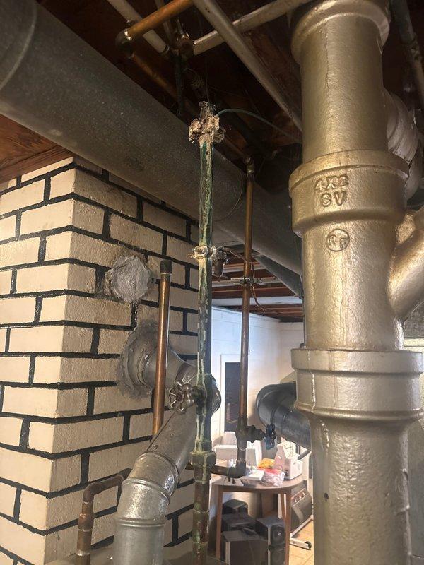 Conducted comprehensive inspection of residential water heater system and associated plumbing. Identified copper pipe deterioration with visible corrosion at connection point. Documented condition of main brass supply line and overall plumbing infrastructure for future reference.